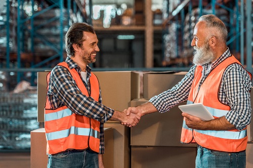 Two men shaking hands orange hi vis